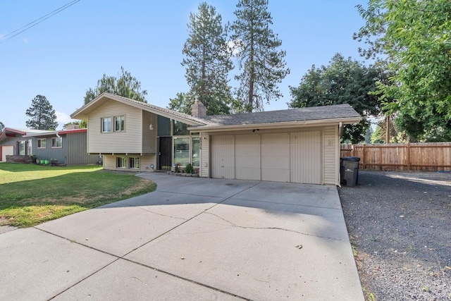 tri-level home with driveway, a front lawn, fence, an attached garage, and a chimney