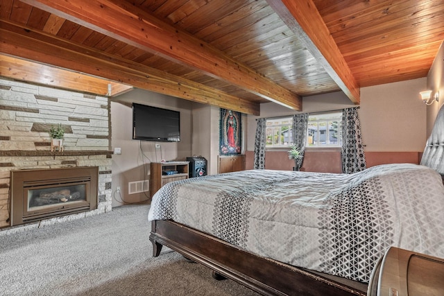 bedroom with visible vents, beam ceiling, carpet, a stone fireplace, and wooden ceiling