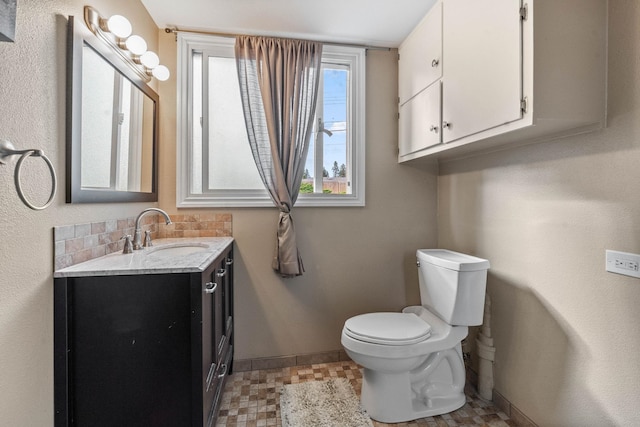 bathroom with baseboards, toilet, and vanity