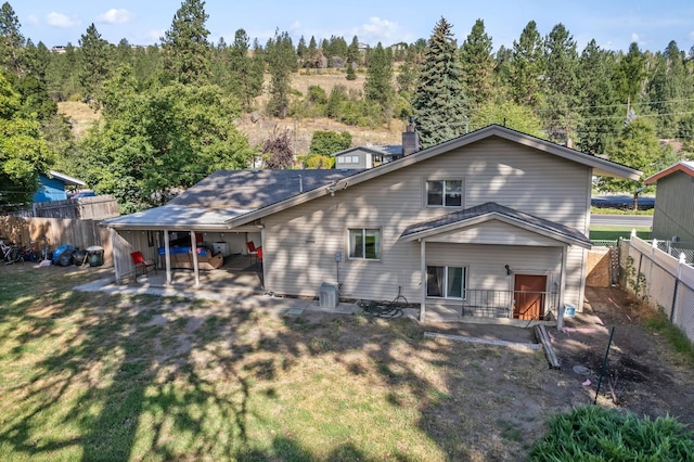 rear view of house featuring a patio, a lawn, a fenced backyard, and a chimney