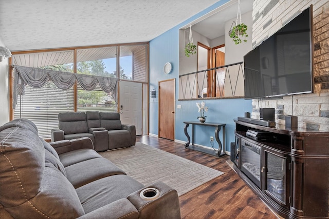 living area with a textured ceiling, wood finished floors, baseboards, and high vaulted ceiling