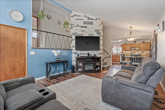 living room with high vaulted ceiling, wood finished floors, a fireplace, baseboards, and stairs