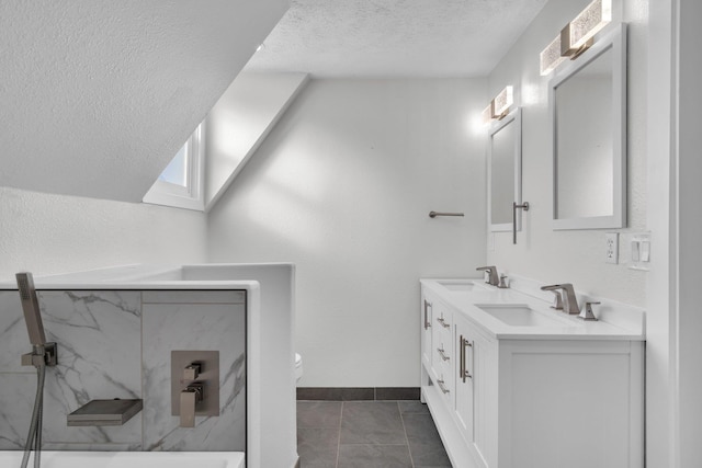 bathroom with a textured ceiling, tile patterned floors, toilet, and a sink