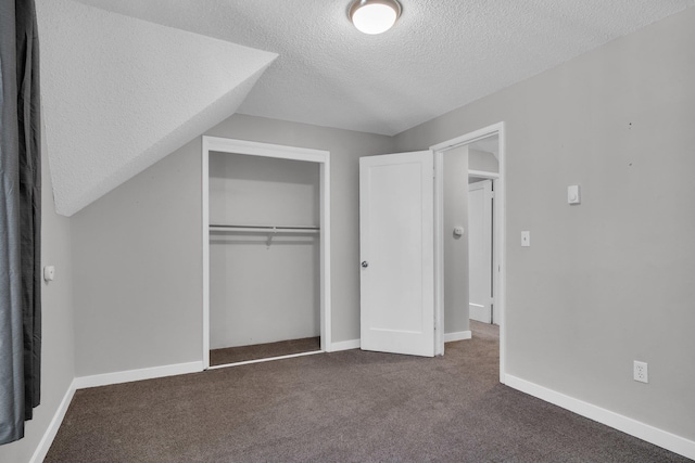 unfurnished bedroom featuring baseboards, dark carpet, vaulted ceiling, a closet, and a textured ceiling