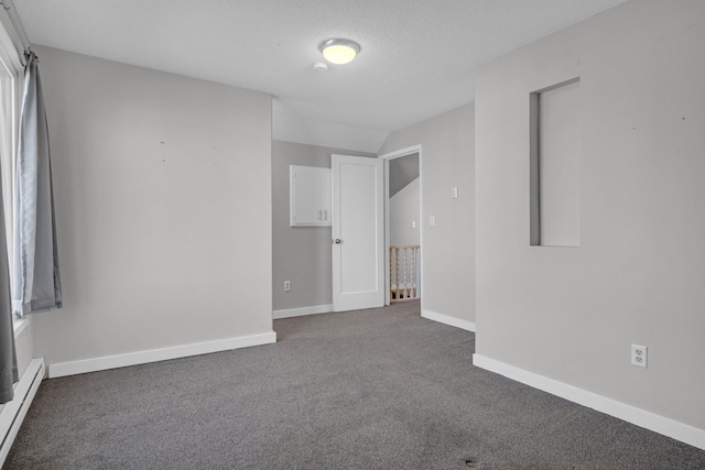 spare room featuring a baseboard heating unit, baseboards, carpet, and a textured ceiling