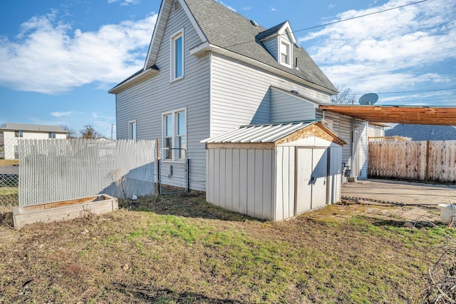 view of side of property with a storage unit, an outbuilding, a lawn, fence, and metal roof