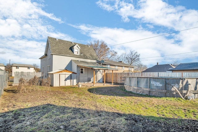 rear view of house featuring a storage unit, an outbuilding, a fenced backyard, a shingled roof, and a fenced in pool