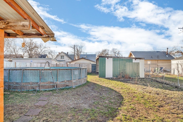 view of yard featuring an outbuilding, a fenced in pool, a storage shed, and fence