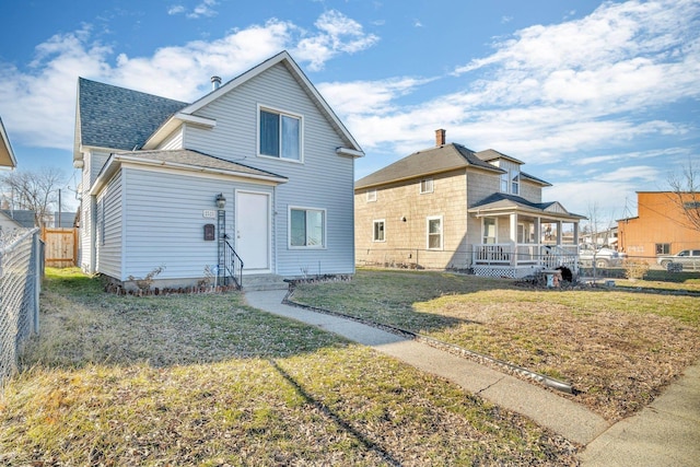 back of house with a yard, fence, and a shingled roof