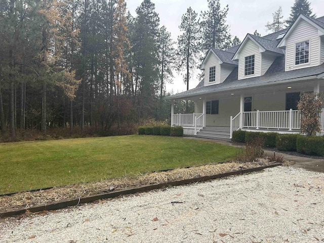 view of front facade featuring covered porch, a front yard, and a shingled roof