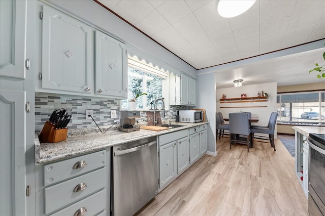 kitchen featuring gray cabinetry, a sink, light wood-style floors, appliances with stainless steel finishes, and decorative backsplash