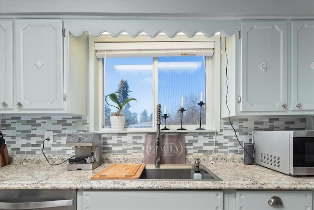 kitchen featuring decorative backsplash, light countertops, white cabinets, and a sink