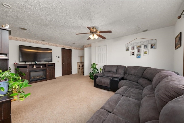 carpeted living area featuring a textured ceiling, a glass covered fireplace, and a ceiling fan