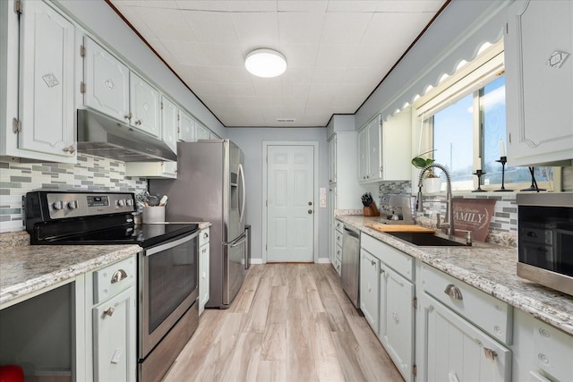 kitchen featuring under cabinet range hood, a sink, white cabinetry, stainless steel appliances, and light wood-style floors