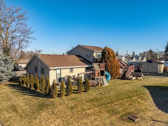 rear view of property featuring a shed, a wooden deck, an outdoor structure, a playground, and a lawn