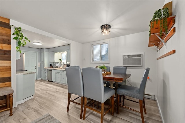 dining space featuring a wall mounted air conditioner, baseboards, baseboard heating, and light wood finished floors