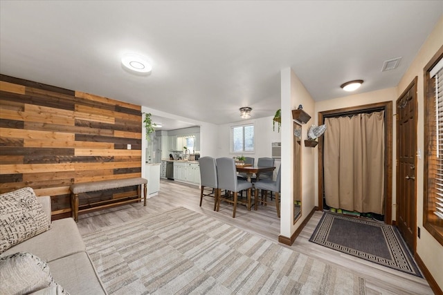 entryway featuring wooden walls, light wood-style flooring, and visible vents