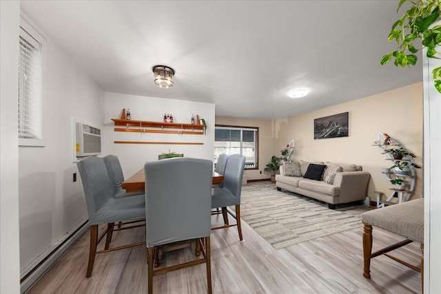 dining room featuring an AC wall unit, light wood-type flooring, a baseboard heating unit, and baseboards