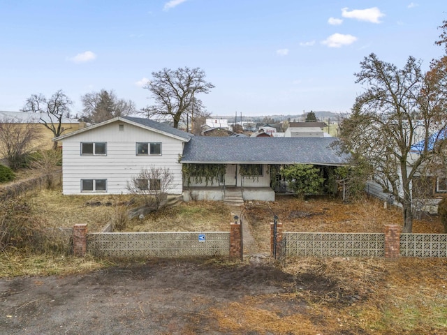 view of front facade with a fenced front yard and a shingled roof