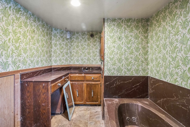 bathroom featuring vanity, wainscoting, a whirlpool tub, and wallpapered walls