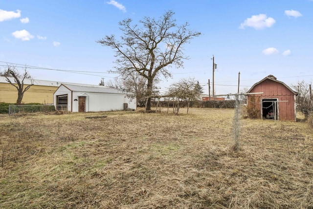 view of yard with a barn, fence, and an outdoor structure