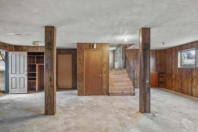 basement featuring stairway, wood walls, and a textured ceiling