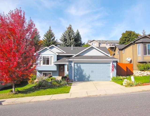 view of front of property featuring an attached garage, driveway, and fence