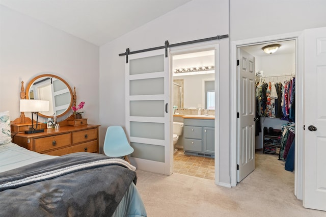 bedroom with a spacious closet, connected bathroom, light colored carpet, a barn door, and a closet