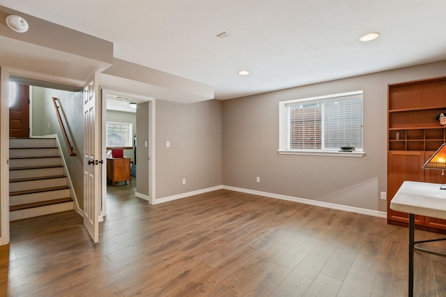 interior space featuring baseboards, a healthy amount of sunlight, wood finished floors, and stairs