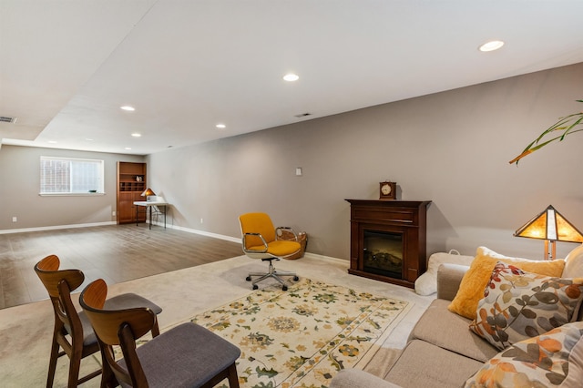 living room featuring visible vents, baseboards, recessed lighting, light wood-style flooring, and a glass covered fireplace