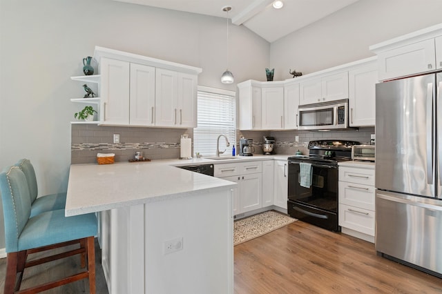 kitchen featuring a peninsula, vaulted ceiling with beams, a sink, appliances with stainless steel finishes, and white cabinetry