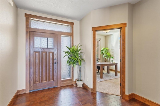 foyer entrance featuring baseboards, wood-type flooring, and a textured ceiling