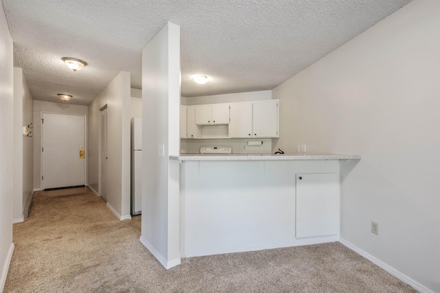 kitchen featuring stove, light colored carpet, light countertops, and freestanding refrigerator