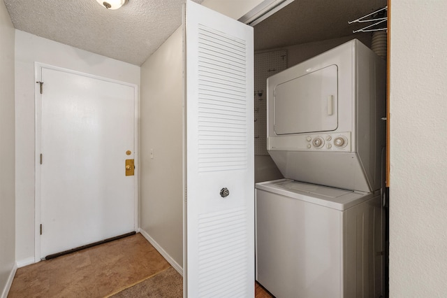 laundry area featuring stacked washer / dryer, a textured ceiling, laundry area, and baseboards