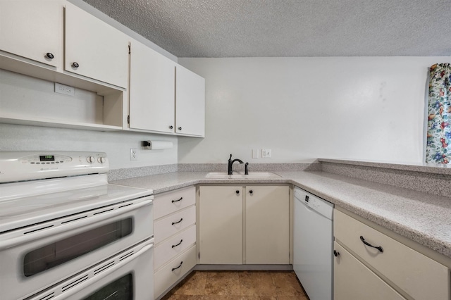 kitchen featuring white appliances, a textured ceiling, light countertops, and a sink