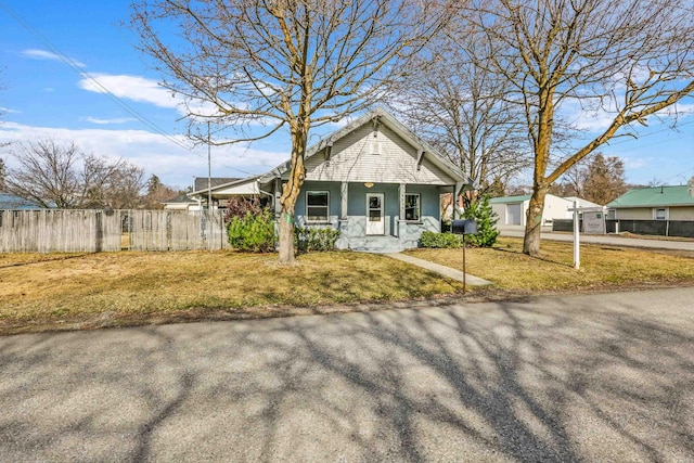 view of front of house with a front lawn, fence, covered porch, and stucco siding