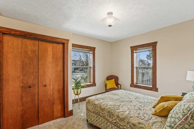 bedroom featuring multiple windows, baseboards, a closet, and light carpet