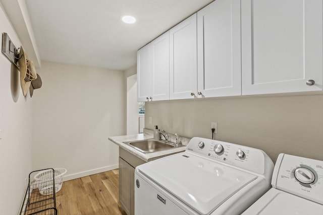 laundry area with baseboards, washer and dryer, light wood-style floors, cabinet space, and a sink