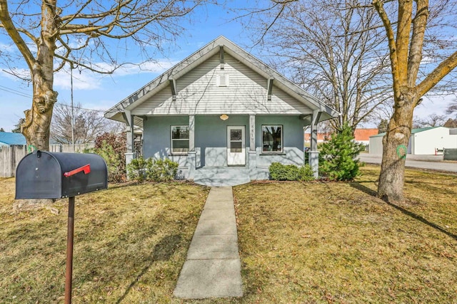 bungalow-style house featuring a front yard, fence, covered porch, and stucco siding