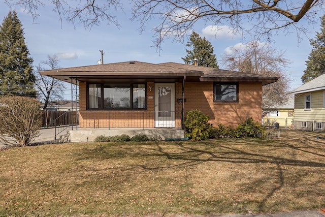 bungalow-style house featuring brick siding, roof with shingles, a front lawn, and fence