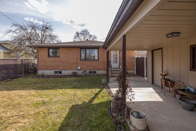 rear view of property with fence, brick siding, a lawn, and entry steps