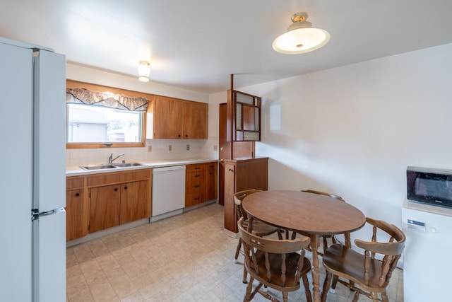 kitchen featuring white appliances, light floors, a sink, light countertops, and backsplash