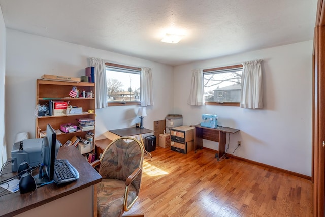 home office featuring light wood-style floors, baseboards, and a textured ceiling