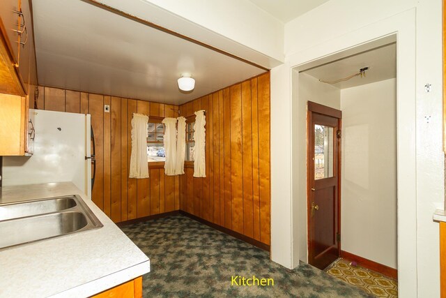 460 E Columbia Ave, Colville, WA 99114 - kitchen with freestanding refrigerator, baseboards, wood walls, a sink, and light countertops