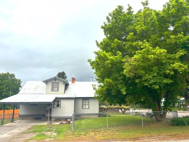 460 E Columbia Ave, Colville, WA 99114 - view of front of house featuring an attached carport, metal roof, driveway, and a chimney