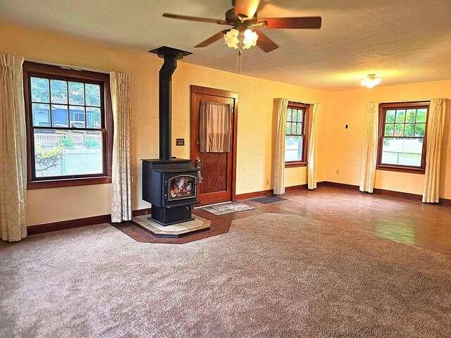 460 E Columbia Ave, Colville, WA 99114 - unfurnished living room with carpet, ceiling fan, a wood stove, baseboards, and a textured ceiling