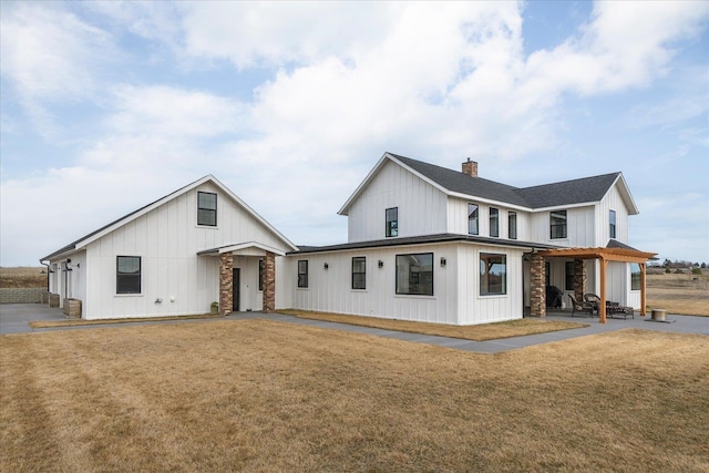 view of front of property featuring stone siding, board and batten siding, a chimney, and a front yard