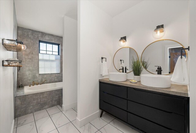 bathroom with double vanity, baseboards, tiled bath, and a sink