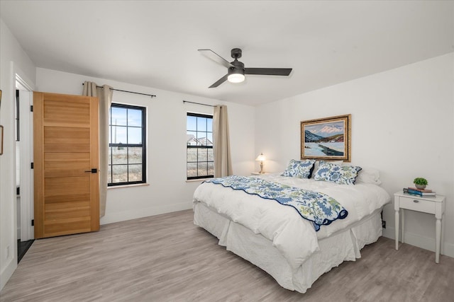 bedroom with baseboards, light wood-style flooring, and a ceiling fan