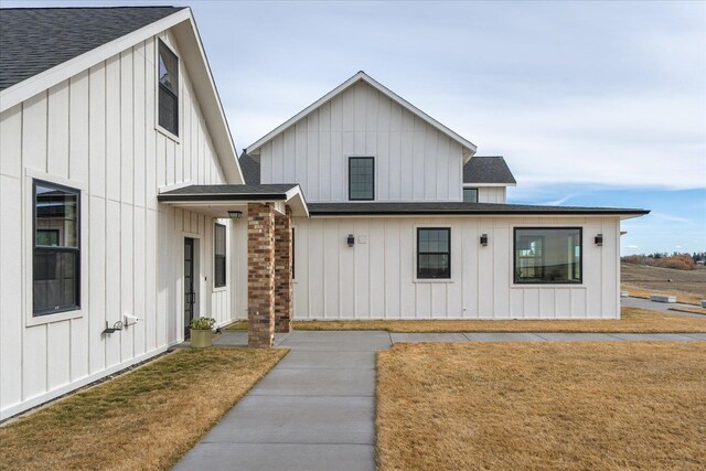 modern farmhouse featuring board and batten siding, a front lawn, and a shingled roof